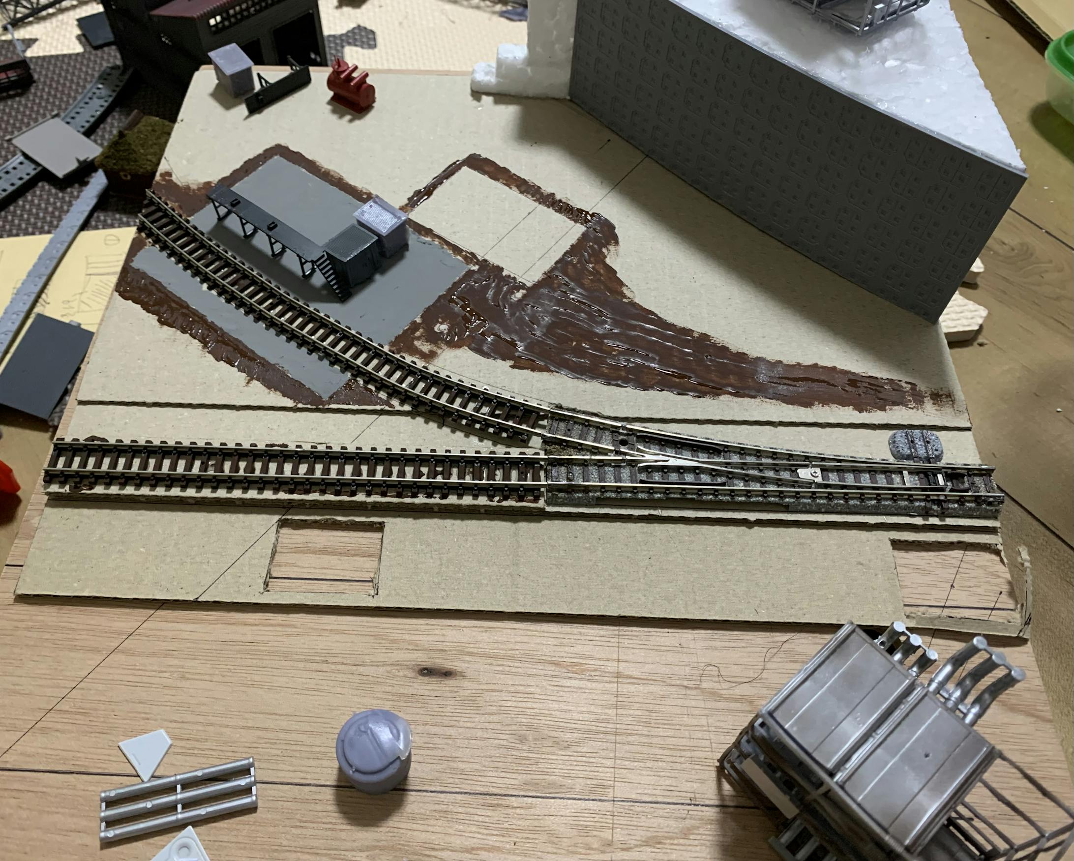 規格通りKATOの複線を設置する場所をペンでマークし、その場所をあけてダンボールを設置します。改めて、レールを仮置きして配置を確認。また、工場には専用線があり、どこか廃線になっていたらステキだなあと思い、専用線、廃線を設置。軌道は、接触不良で手元に余っていたTOMIXのレールを使用しました。試しに、建物箇所、地面とイメージしやすいように色をつけてみました。 規格通りKATOの複線を設置する場所をペンでマークし、その場所をあけてダンボールを設置します。改めて、レールを仮置きして配置を確認。また、工場には専用線があり、どこか廃線になっていたらステキだなあと思い、専用線、廃線を設置。軌道は、接触不良で手元に余っていたTOMIXのレールを使用しました。試しに、建物箇所、地面とイメージしやすいように色をつけてみました。