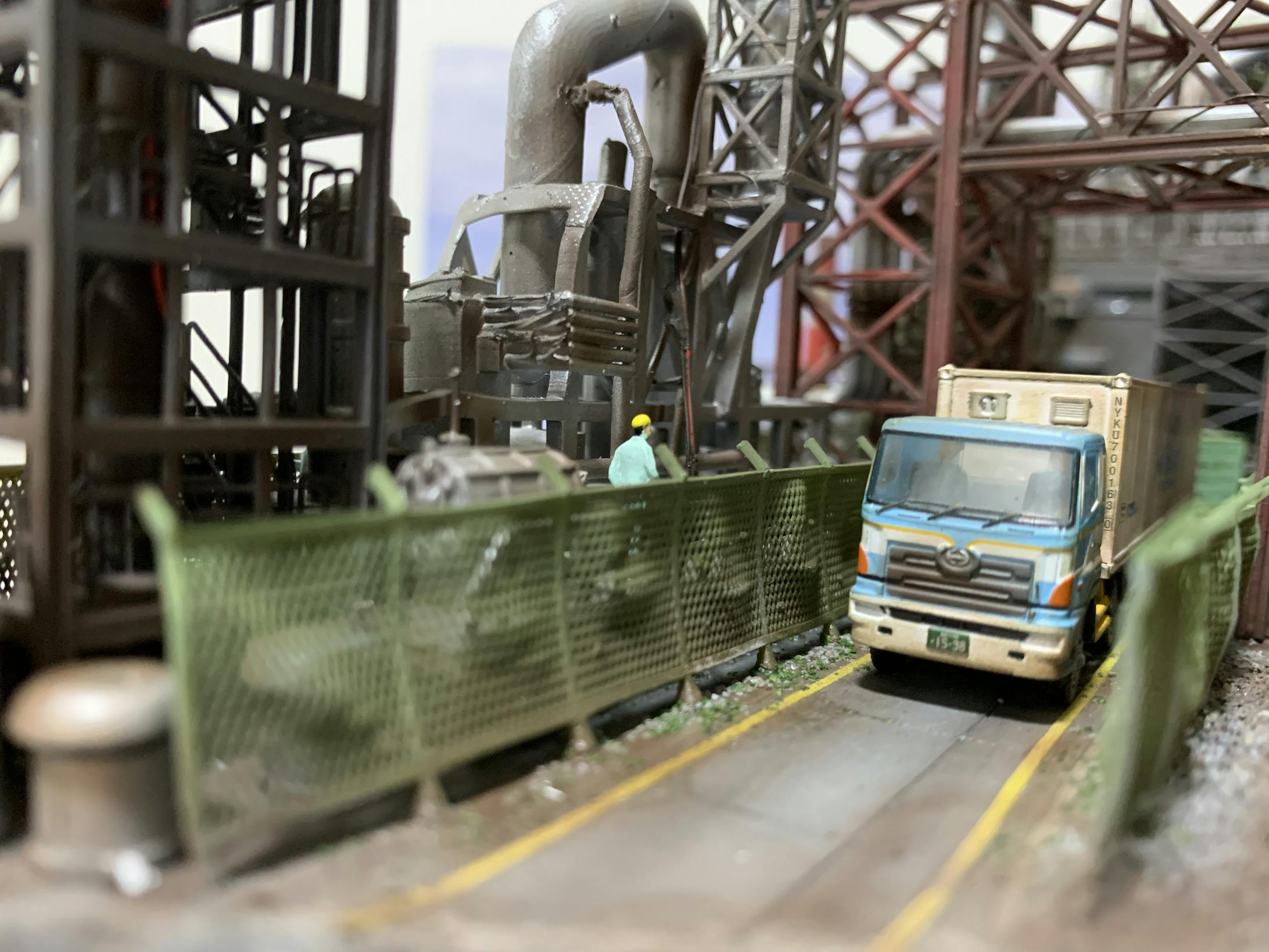 トラックに乗ってる人と作業員があいさつを交わしています。トラックは狭い工事敷地内を注意しながら走行しています。
