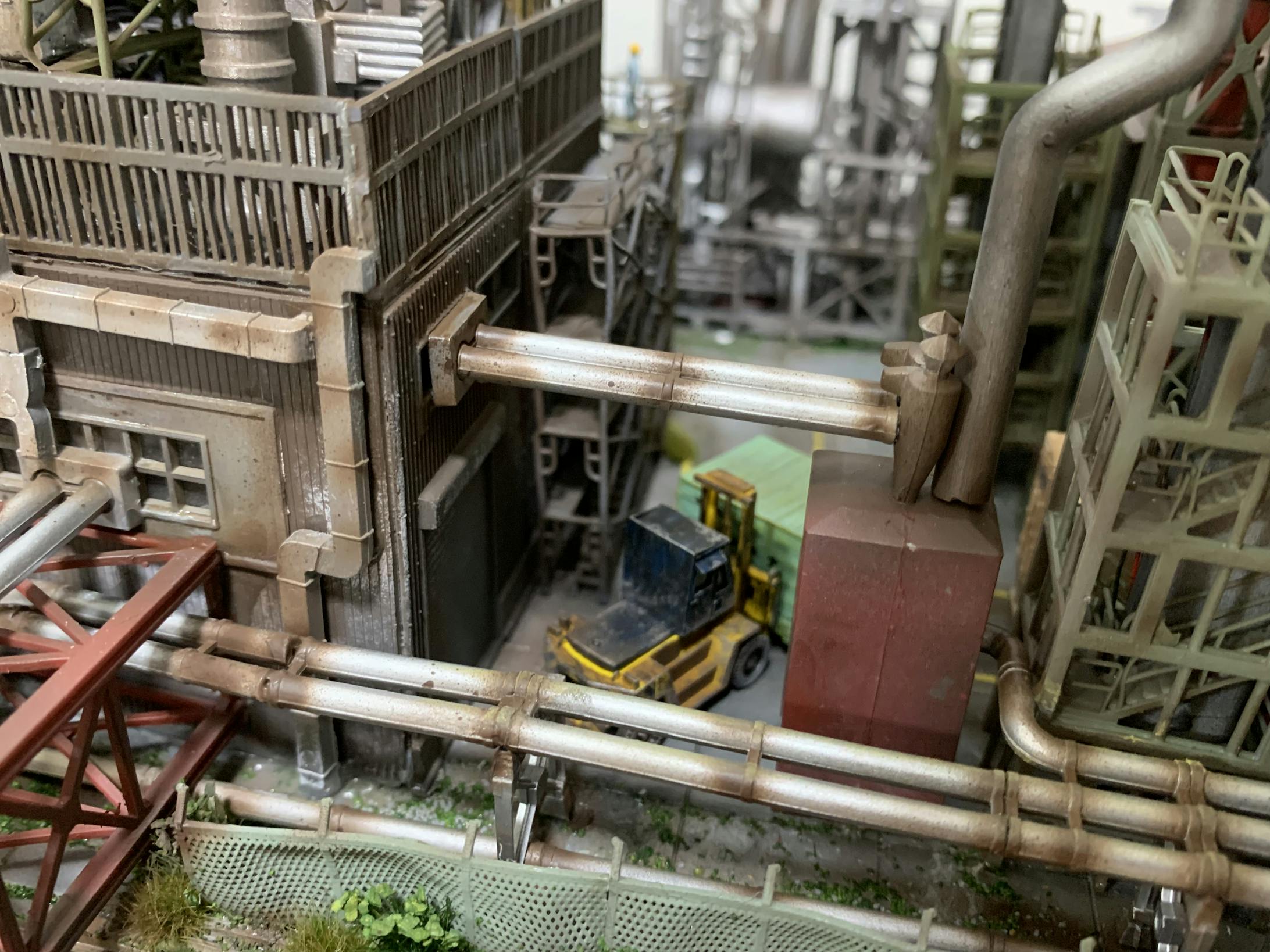 工場の奥に進むとフォークリフトが配管が入り組んだ狭い工場敷地内で、建屋の中にあったコンテナを移動させています。